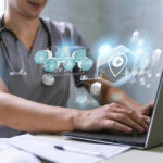 Healthcare professional using a laptop with digital medical icons representing telemedicine, electronic health records, and modern healthcare technology